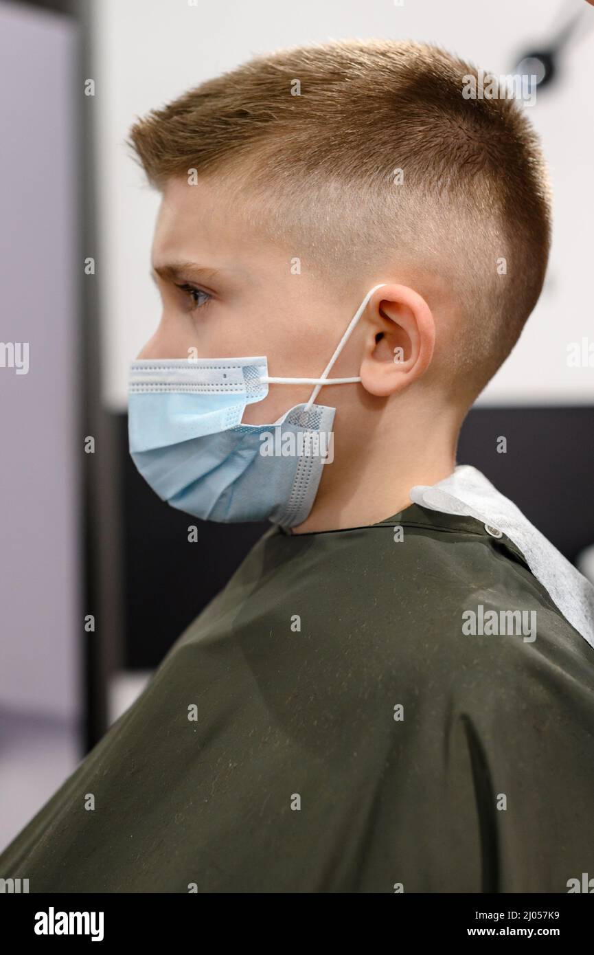 Colegial en una peluquería durante una pandemia, elegante corte de pelo  para el bebé, peinado con gel y secador de pelo Fotografía de stock - Alamy
