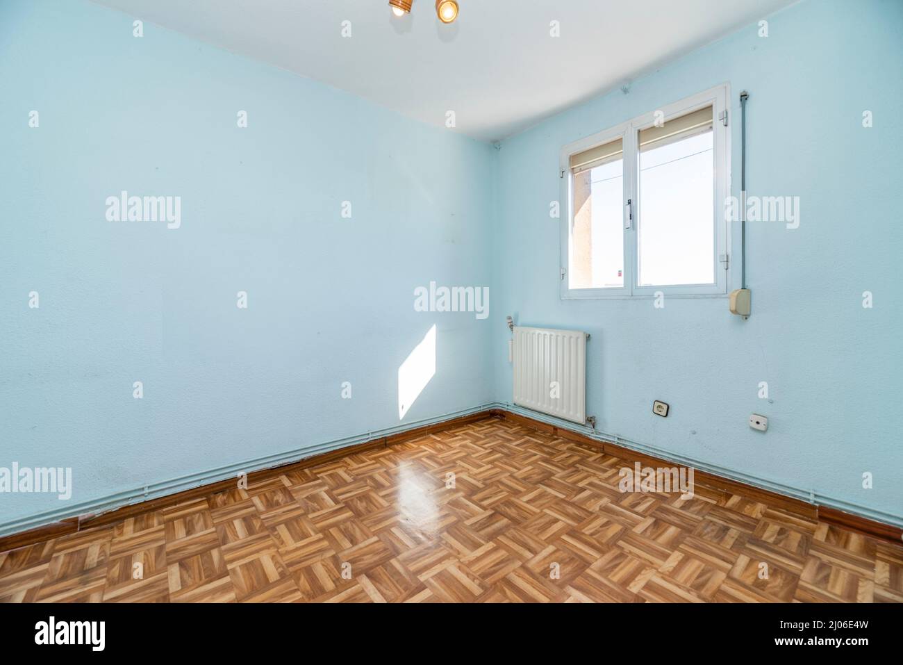 Sala de estar vacía con suelo de parqué, paredes pintadas de azul y radiador  de aluminio blanco Fotografía de stock - Alamy