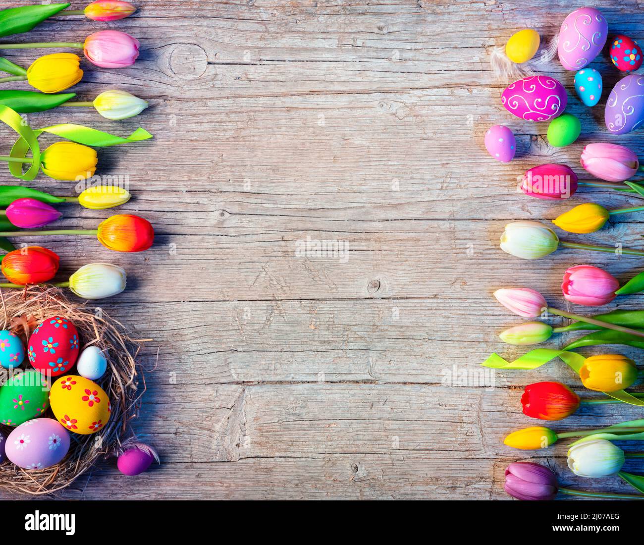 Tablero de Pascua con decoración de huevos y tulipanes en mesa de madera natural Foto de stock
