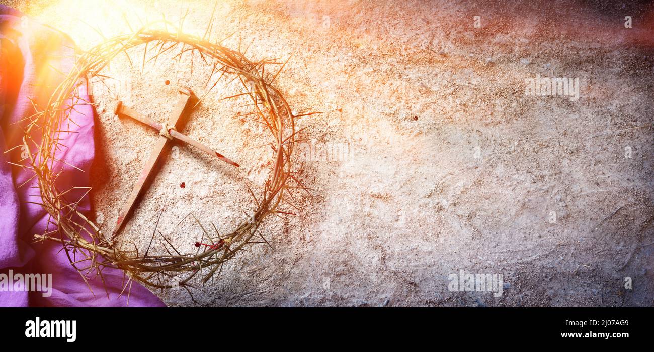 Pasión y Crucifixión de Jesús - Corona de Espinas y Clavos Sanguinos y Robe Púrpura en Tierra con Luz del Sol y Enfoque Selectivo Foto de stock