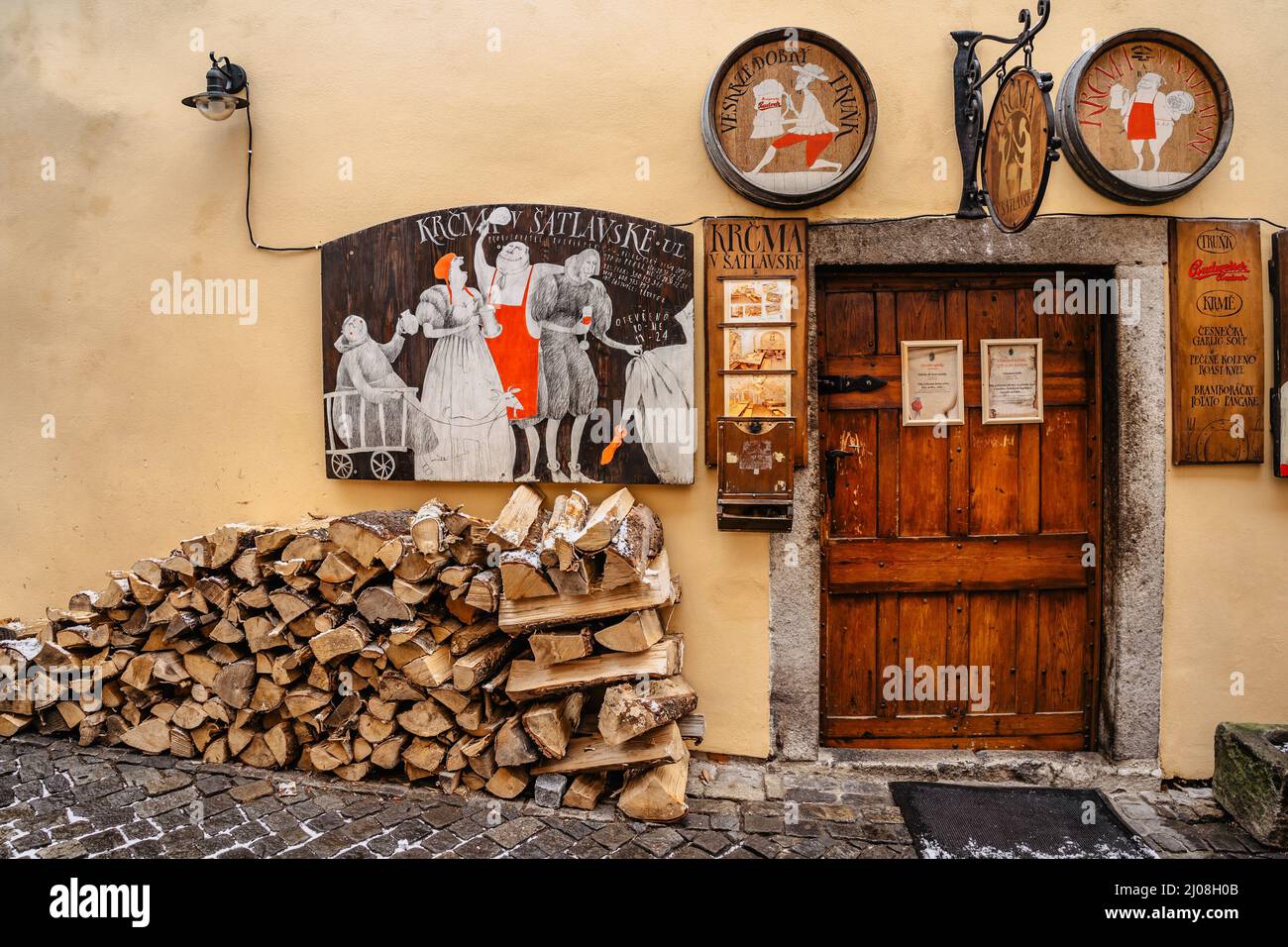 Cesky Krumlov,República Checa-Marzo 5,2022.Entrada puerta de madera al pub checo tradicional.Señales decorativos vintage, menú de comida y bebida, fachada colorida Foto de stock
