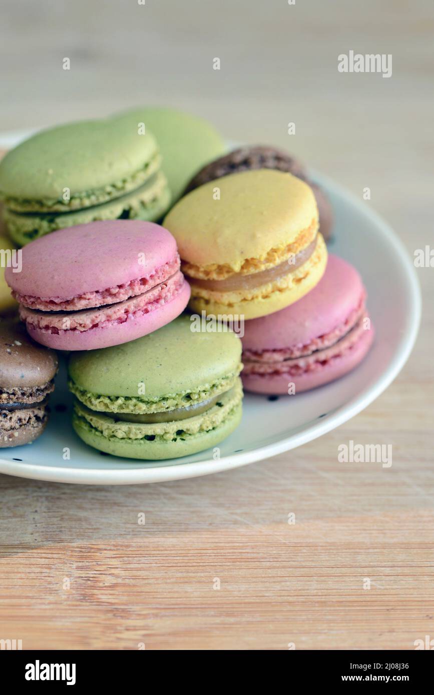 Plato lleno de macarones de frambuesa, limón, pistacho y chocolate Foto de stock