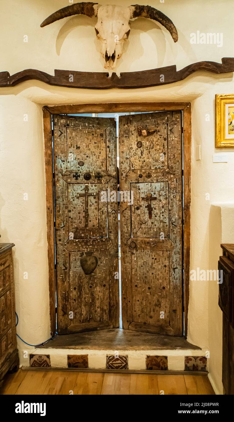 antigua puerta mexicana cubierta en milagros, pequeños encantos religiosos de metal asociados con milagros y bendiciones de santos Foto de stock