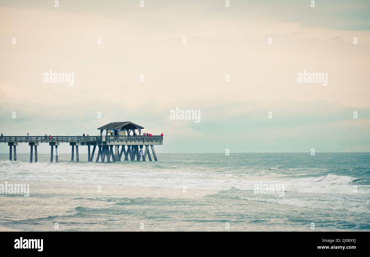 Los turistas pescan en el muelle de pesca de Tybee Island en un día nublado. Foto de stock