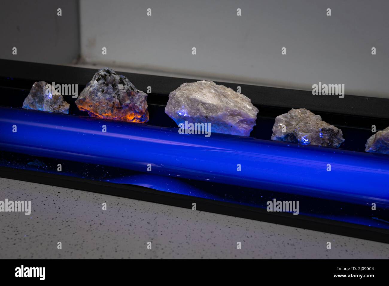 Las piedras en un laboratorio se iluminan con una lámpara ultravioleta, también conocida como 'luz negra' y muestran fluorescencia Foto de stock