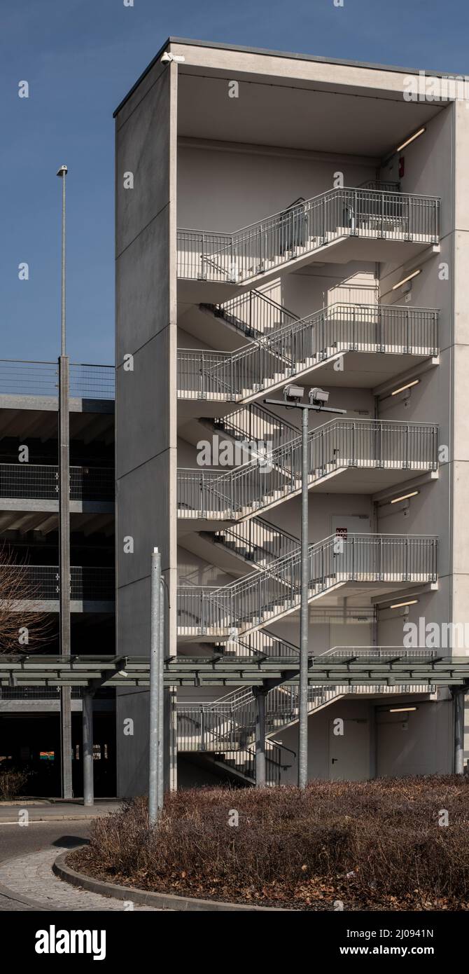 una torre en un aparcamiento con una escalera abierta con escalones de cemento y barandilla metálica Foto de stock