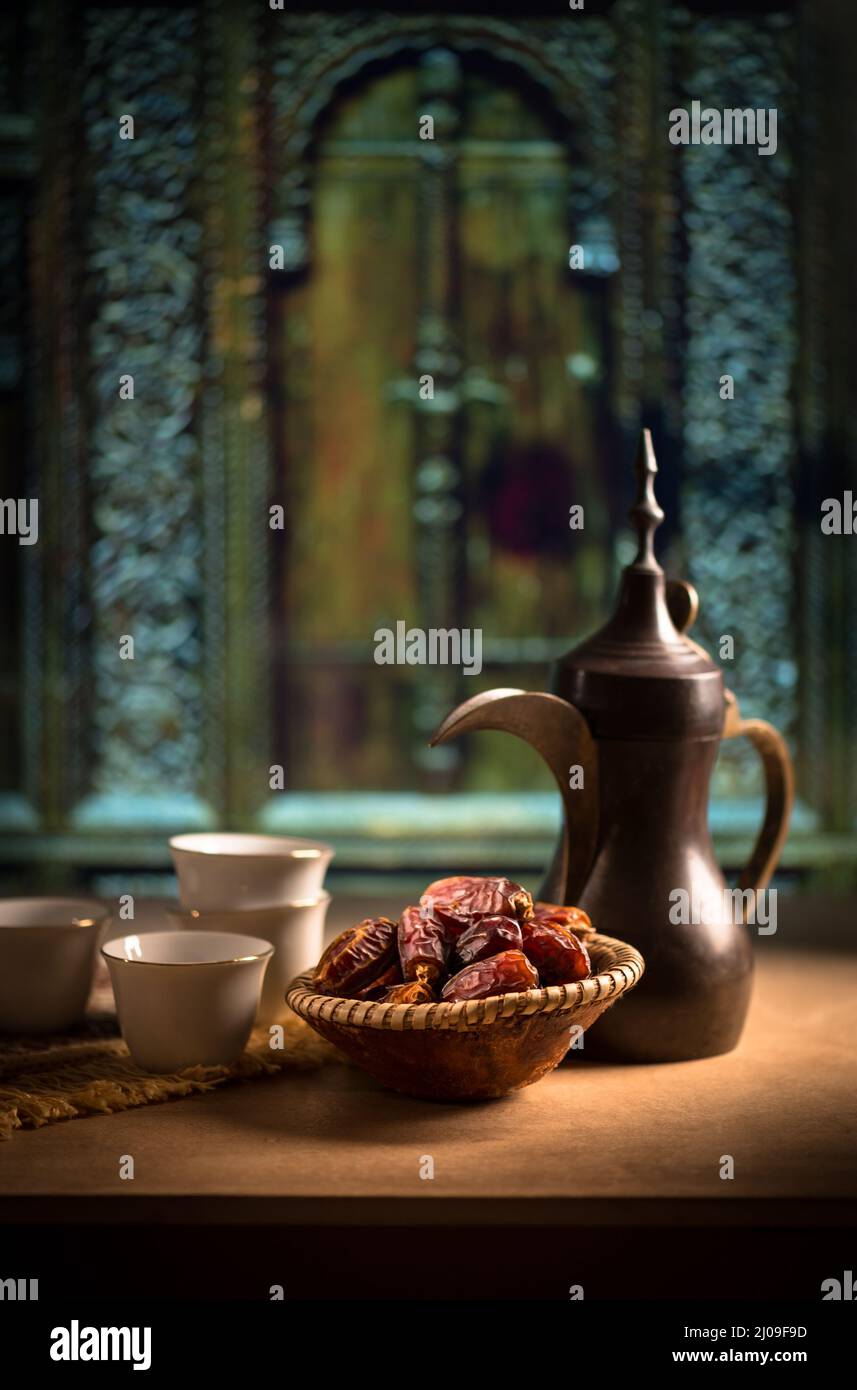 Hermosa vida de una antigua cafetera árabe y dátiles. Comida y bebida tradicional del Medio Oriente en un ambiente rústico. Foto de stock