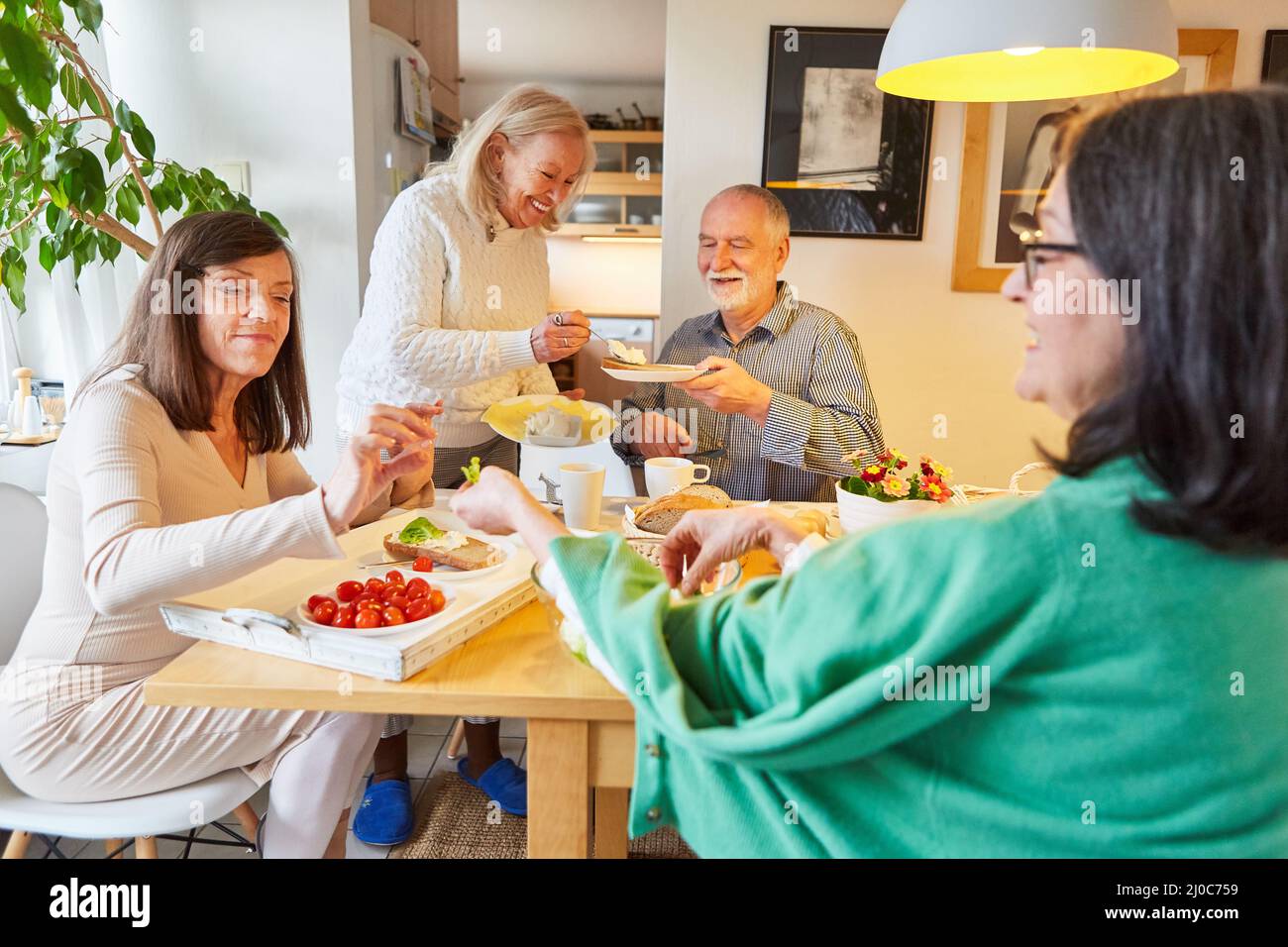 Grupo de personas mayores tomando desayuno o brunch juntos en la cocina compartida Foto de stock