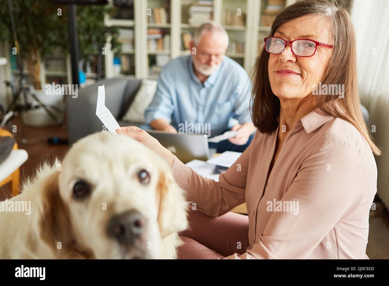 Mujer anciana con un recibo que hace la declaración de impuestos con su marido en el fondo Foto de stock