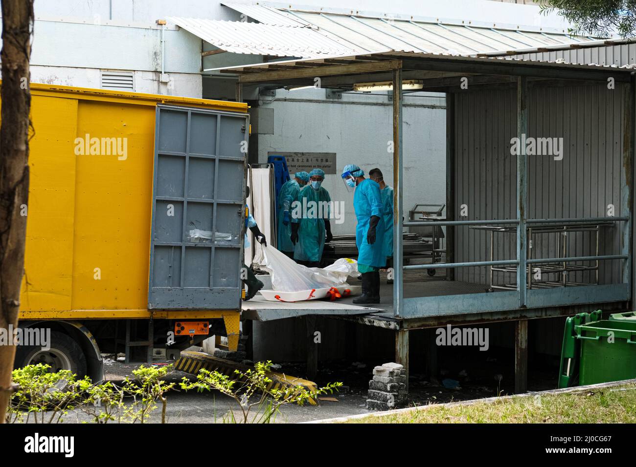 Hong Kong, China. 18th Mar, 2022. Los trabajadores con PPE transportan  cuerpos a un camión en un depósito de cadáveres público. Las autoridades  sanitarias de Hong Kong han establecido contenedores de transporte