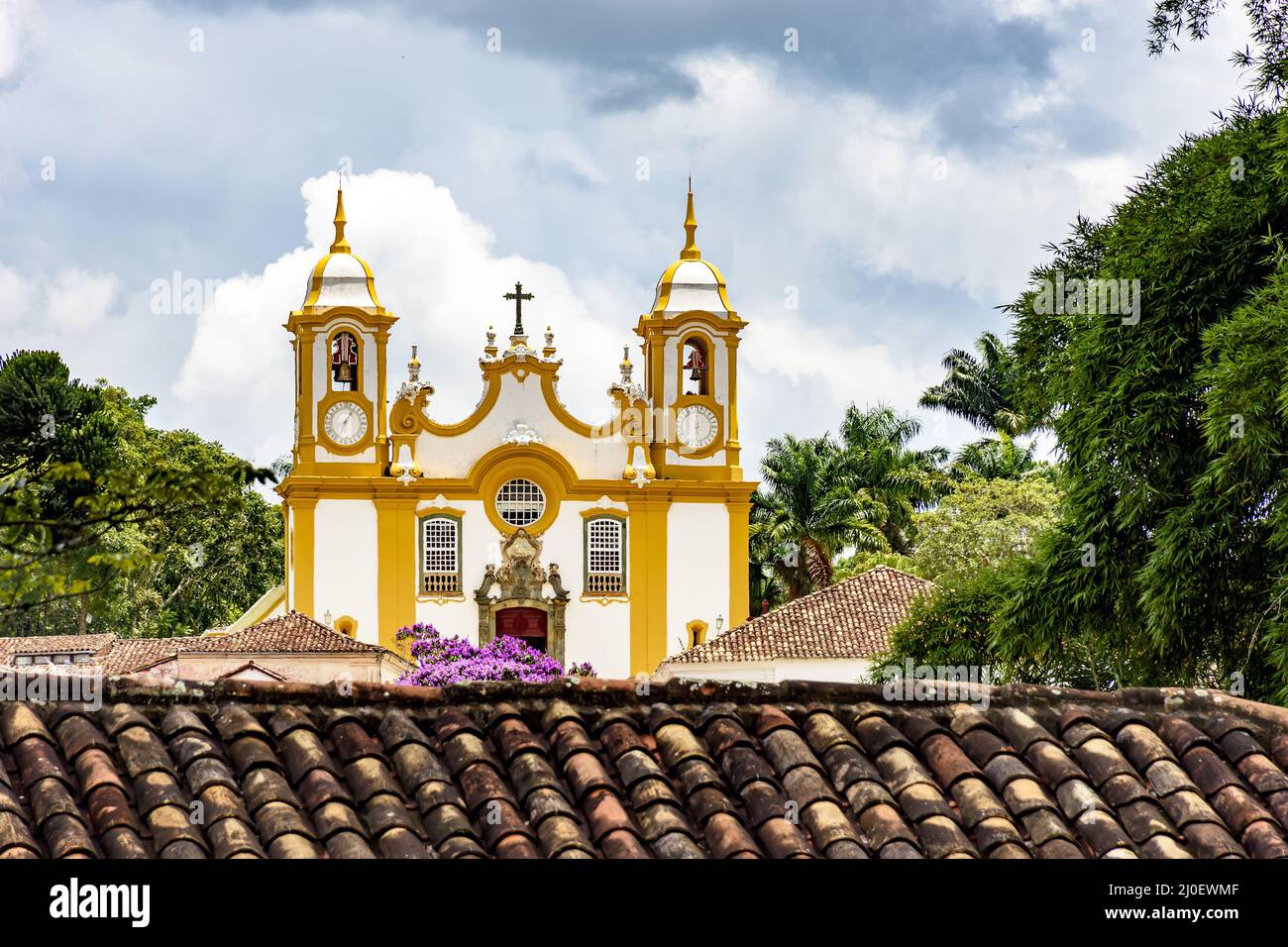 Vista de la iglesia histórica entre tejados y vegetación en la ciudad de Tiradentes Foto de stock