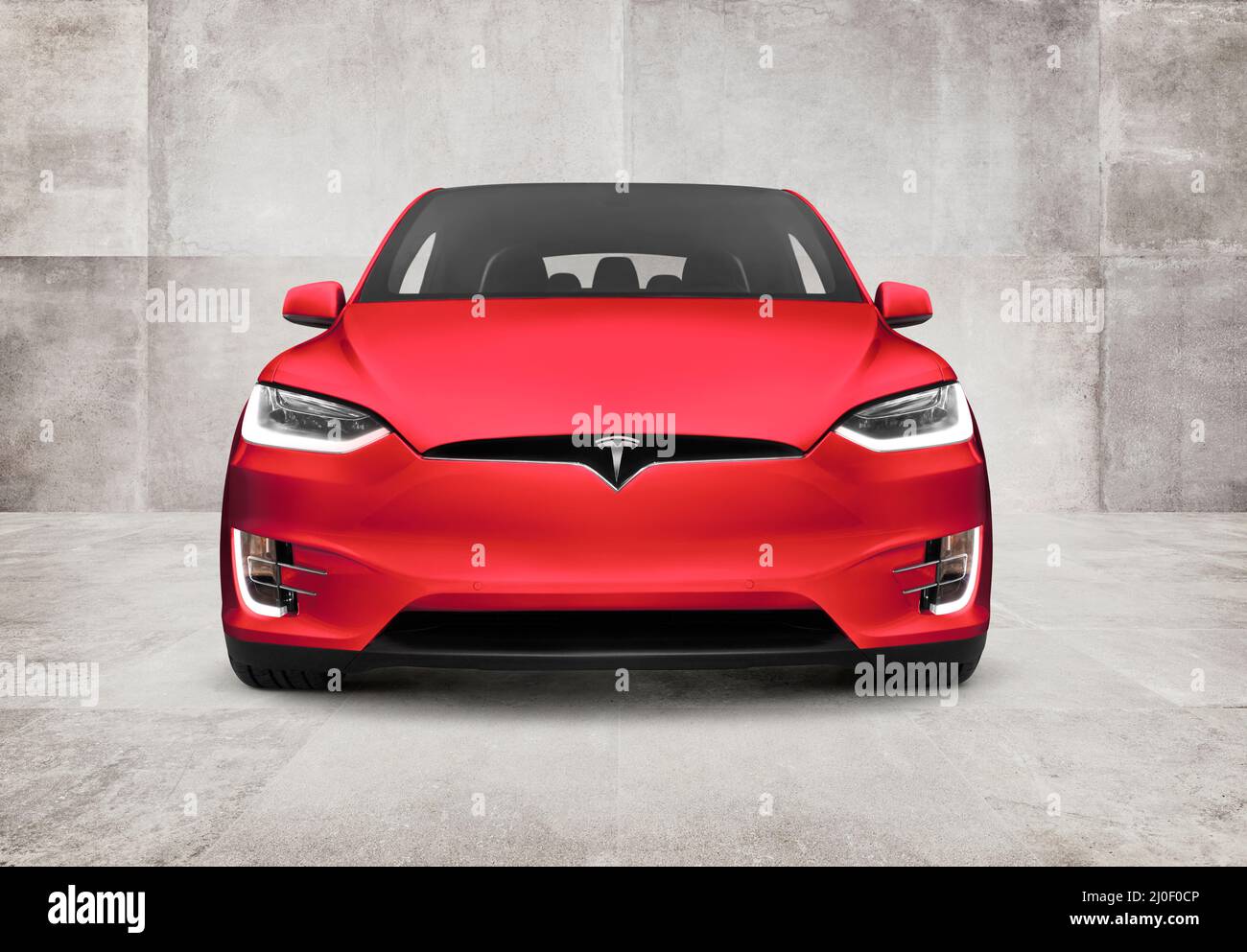 Vista frontal del vehículo eléctrico SUV de lujo Red Tesla Model X sobre fondo de pared de hormigón Foto de stock