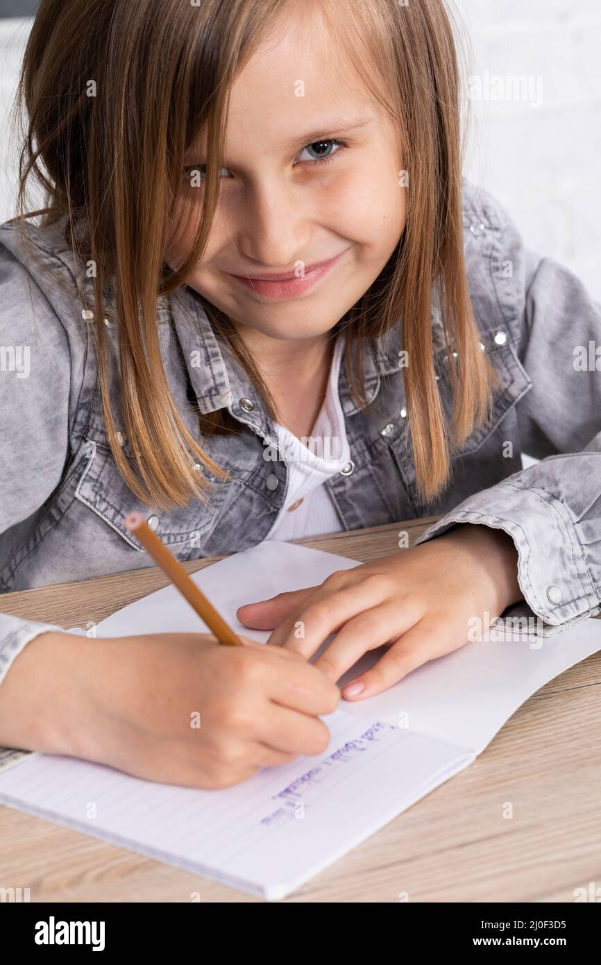 El estudiante dibuja con crayones en el cuaderno de la escuela de oso de peluche como el tema de la lección de hoy. Foto de stock