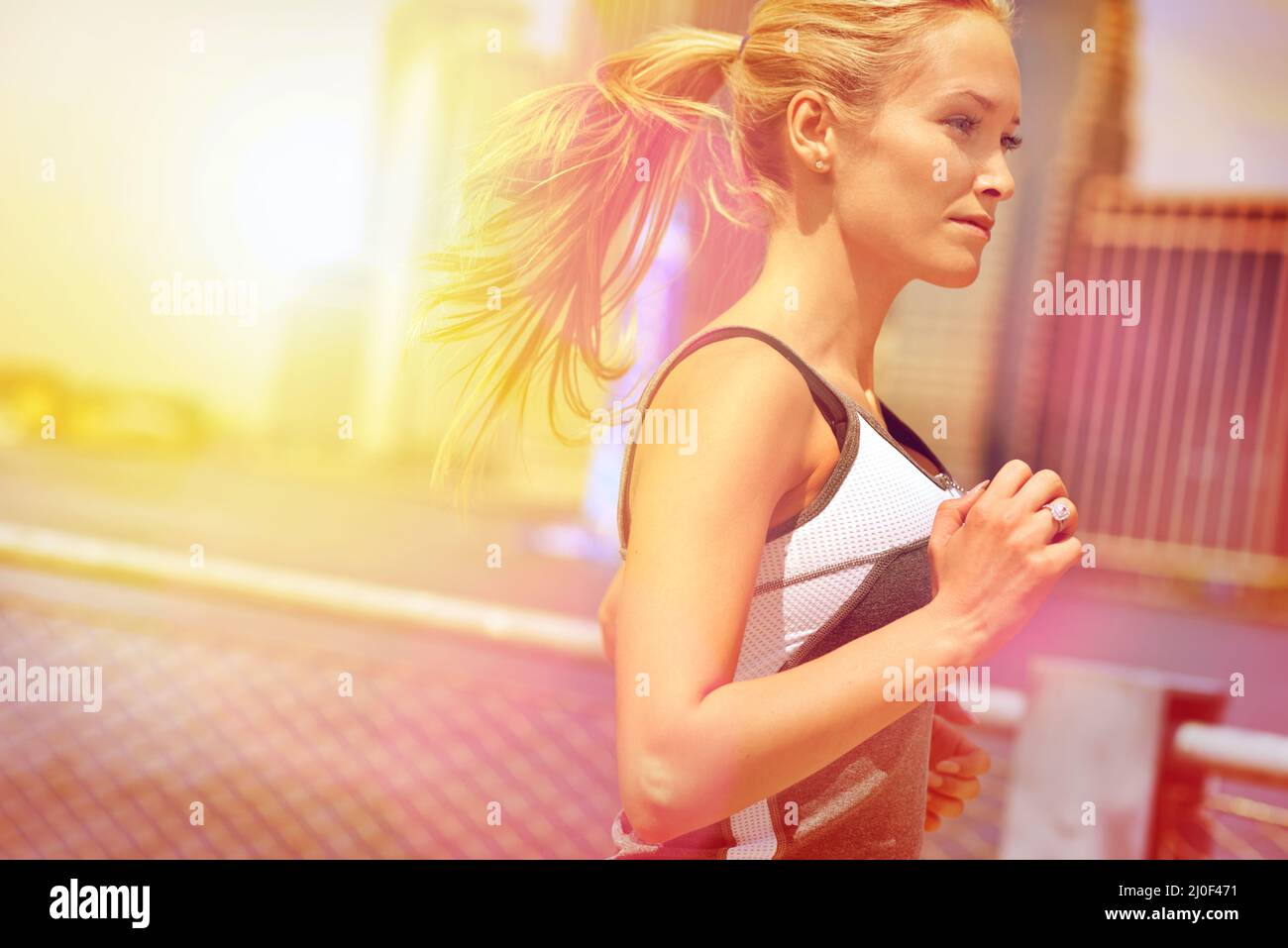 Corriendo en la selva urbana. Foto de una atractiva mujer rubia corriendo en la ciudad. Foto de stock