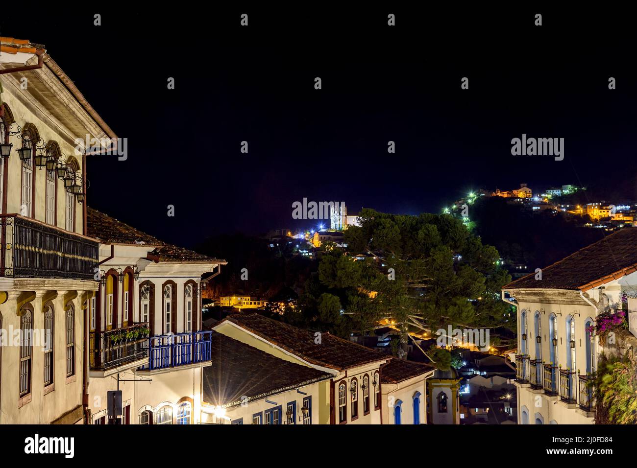 Fachadas de casas de arquitectura colonial en una antigua calle empedrada iluminada por la noche con gran altura Foto de stock
