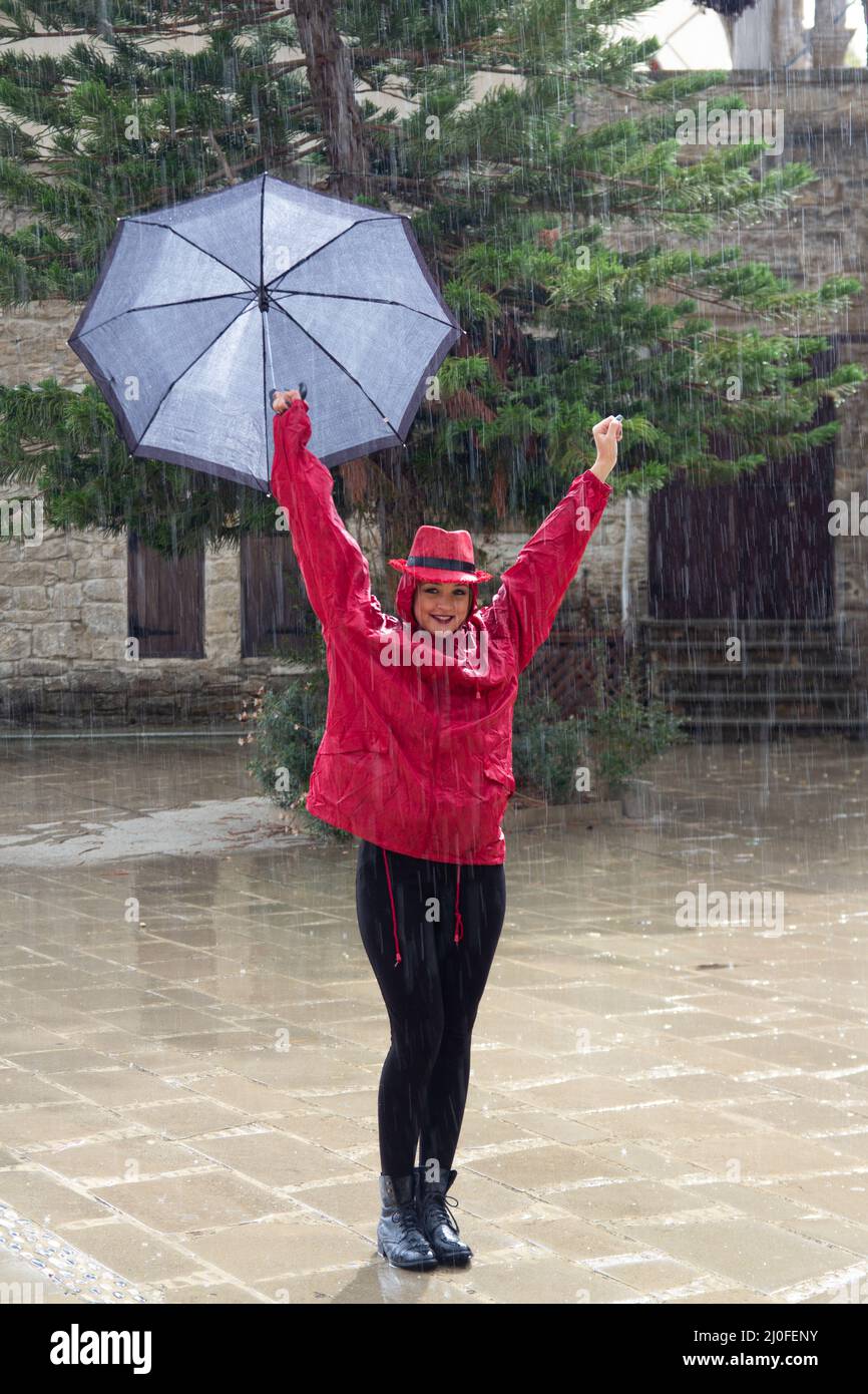 Joven mujer feliz con un paraguas bailando bajo la lluvia Fotografía de  stock - Alamy