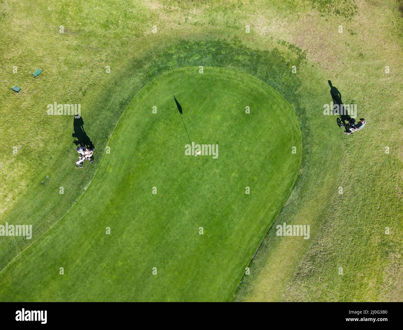 Vista aérea de los jugadores de golf alrededor de la bandera en el agujero en el campo de golf Foto de stock