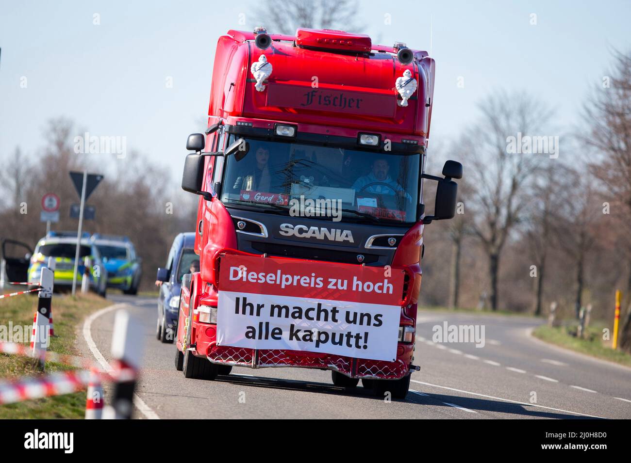 Bergheim, Alemania. 19th Mar, 2022. Con una pancarta que indica que el precio del diésel es demasiado alto, ¡nos romperá a todos! En la parte delantera de un camión, un camión deja una demostración de conductores de camiones contra los altos precios del combustible en un estacionamiento frente al emplazamiento de RWE Rheinbraun AG. Crédito: Thomas Banneyer/dpa/Alamy Live News Foto de stock