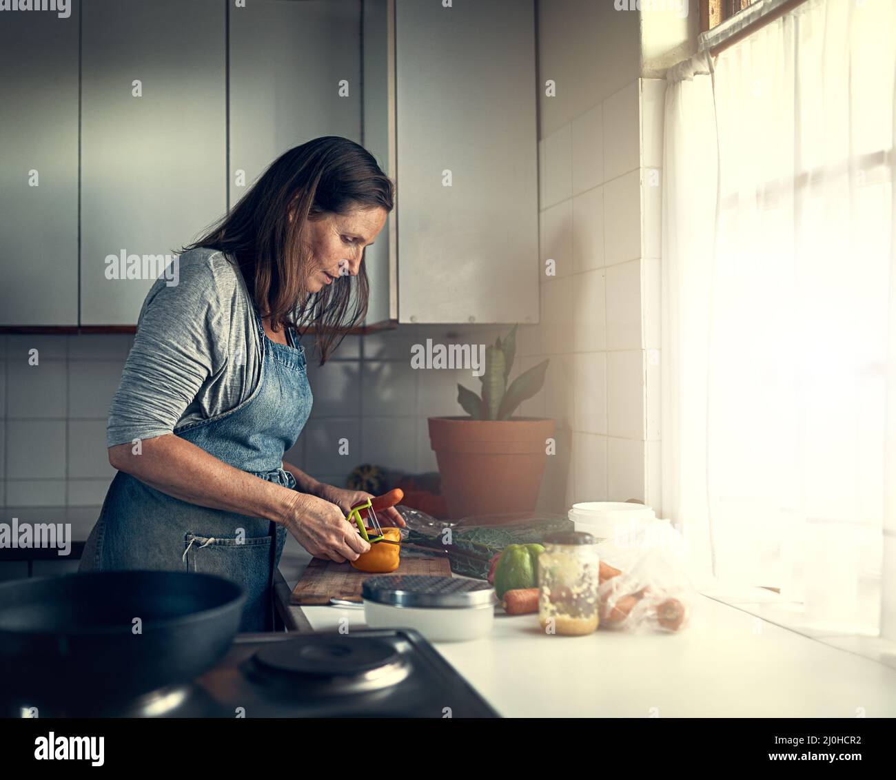 Es un gran cocinero casero. Disparo de una mujer madura preparando una comida en su cocina en casa. Foto de stock