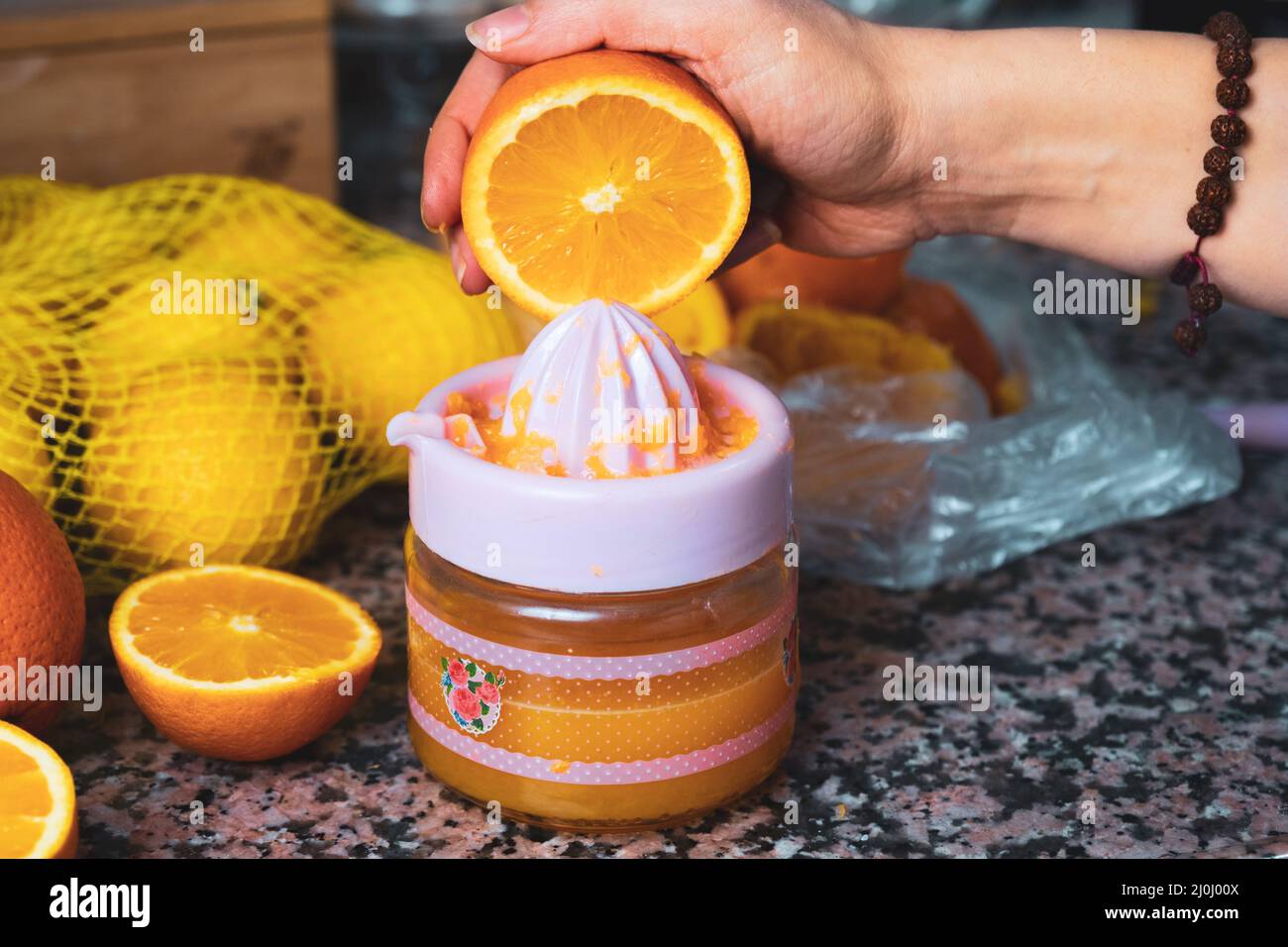 Mujer exprimiendo naranja con exprimidor o exprimidor sobre el fondo la encimera de la cocina. Sin azúcar ni azúcar, proceso de preparación de jugo de naranja delicioso Fotografía de stock -