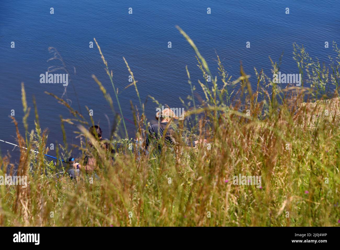 Dos mujeres pescan en las orillas del lago Claiborne. Están escondidos por el banco y los pastos altos en su punto secreto favorito. Foto de stock