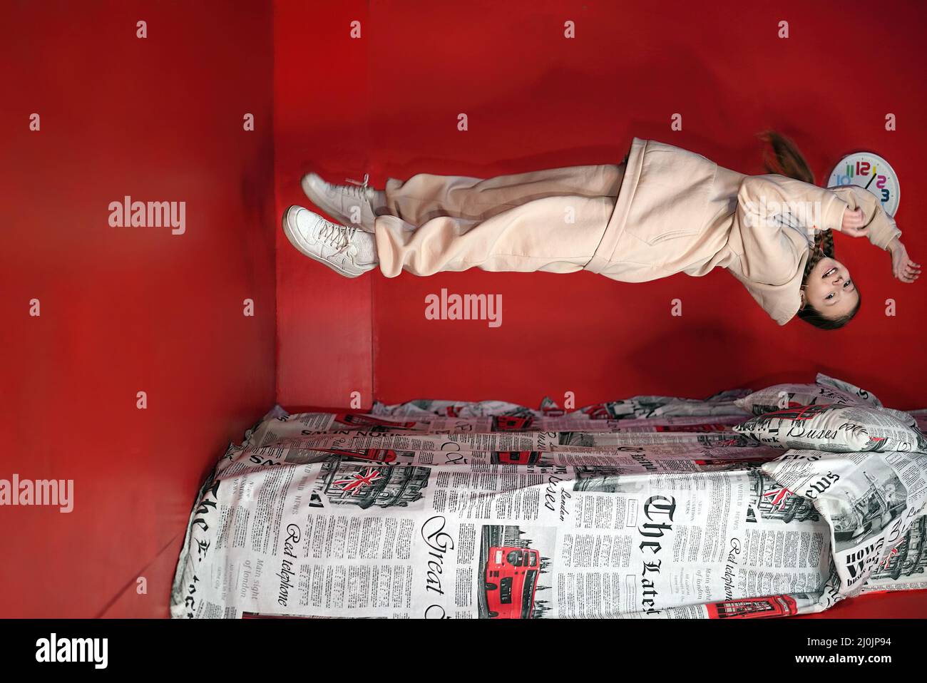 una chica de ilusión que se caiga en la cama en una habitación roja Foto de stock