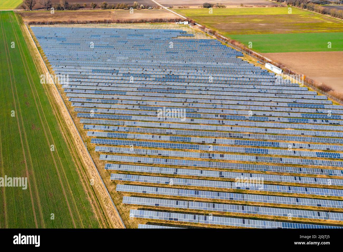 Una planta solar montada en tierra con paneles solares entre campos y prados en Alemania desde una vista de drone Foto de stock