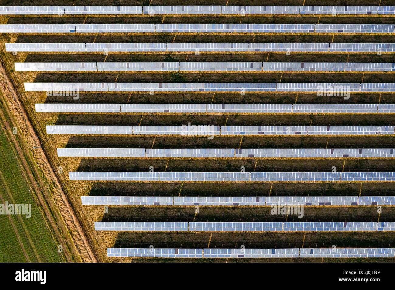 Paneles fotovoltaicos de un sistema montado en tierra junto a un campo en Alemania visto por drone Foto de stock