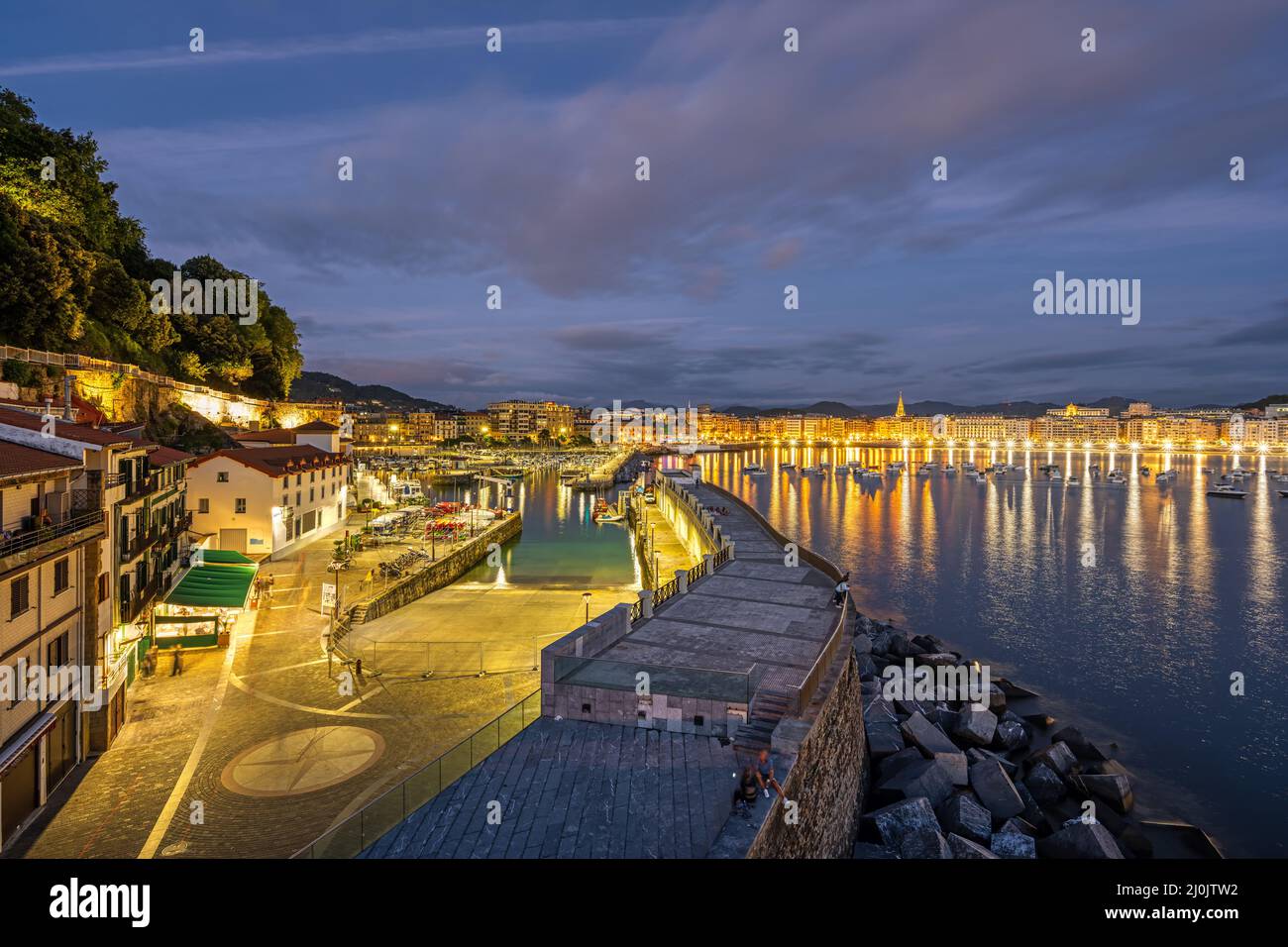 El puerto de San Sebastián con la ciudad en la parte de atrás por la noche Foto de stock