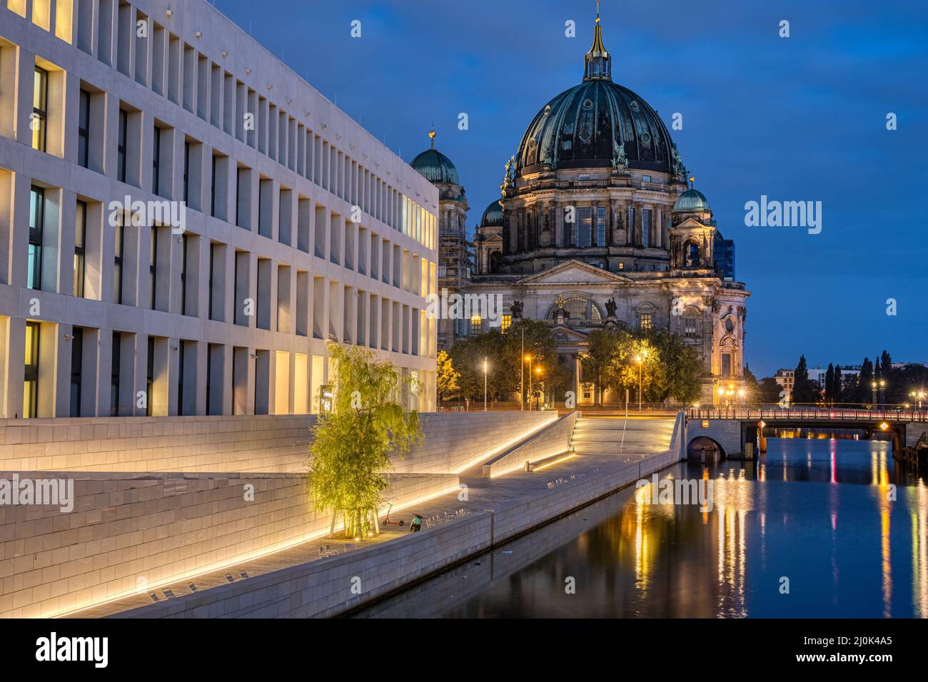 La imponente Catedral de Berlín y la moderna parte trasera del Palacio de la Ciudad por la noche Foto de stock