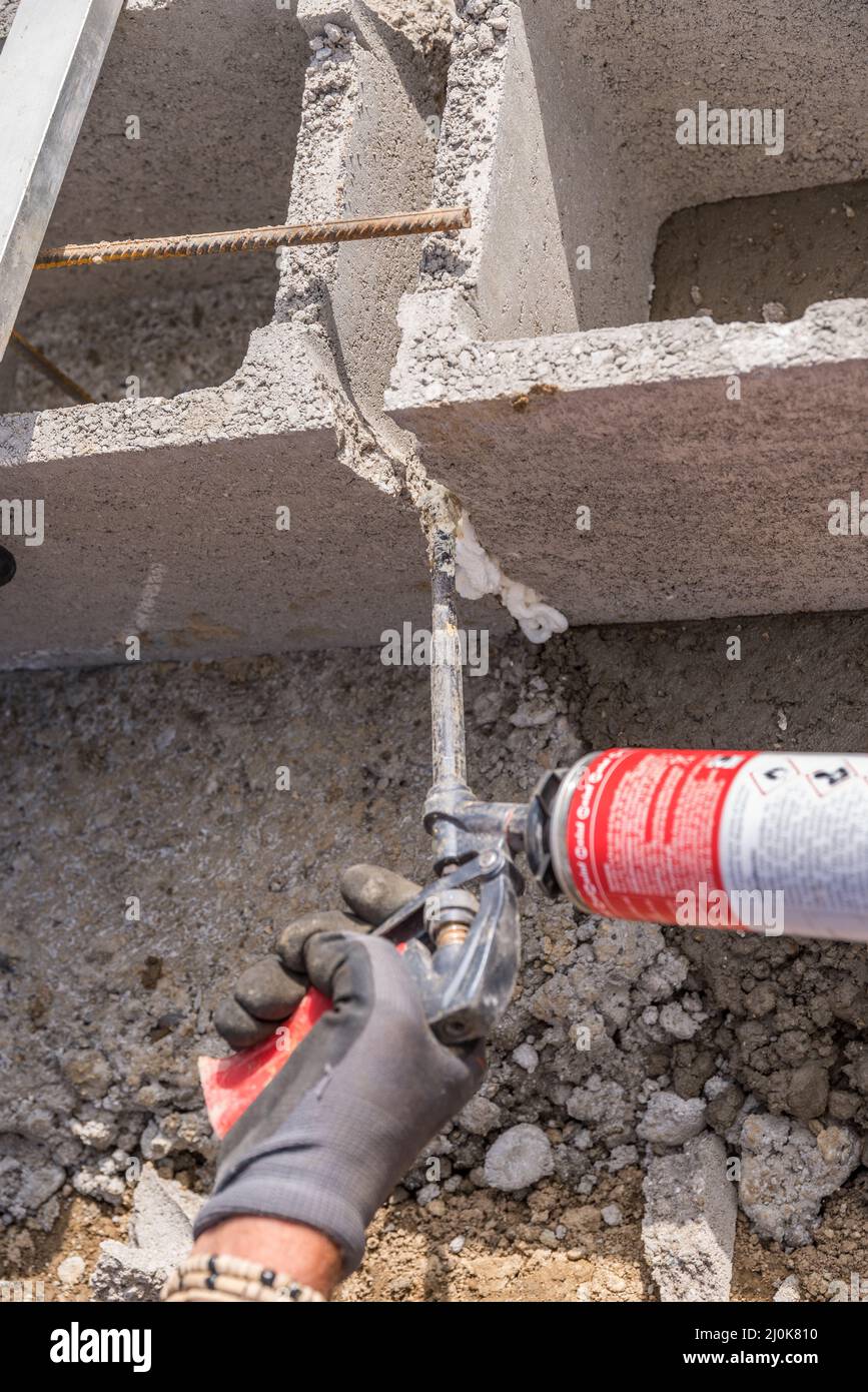 Un trabajador cualificado trabaja en la construcción con espuma de relleno - industria de la construcción Foto de stock