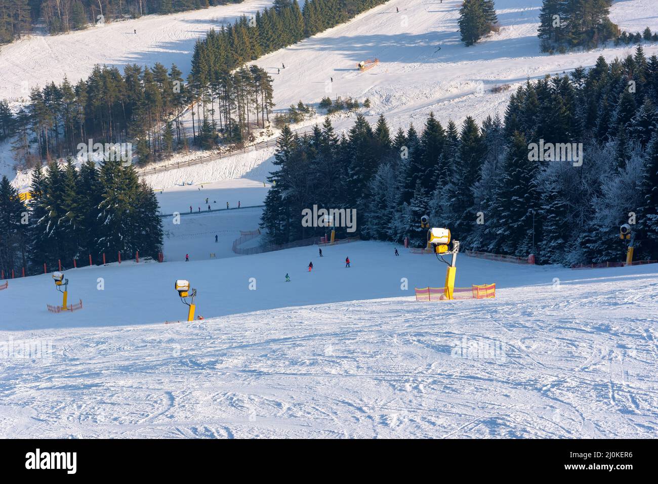 Los esquiadores bajan por la pista en la estación de esquí Slotwiny Arena en un día soleado, Krynica Zdroj, Polonia Foto de stock