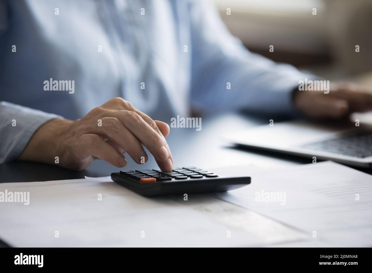 Vista de primer plano mujer sentarse en el escritorio de uso calculadora y portátil Foto de stock