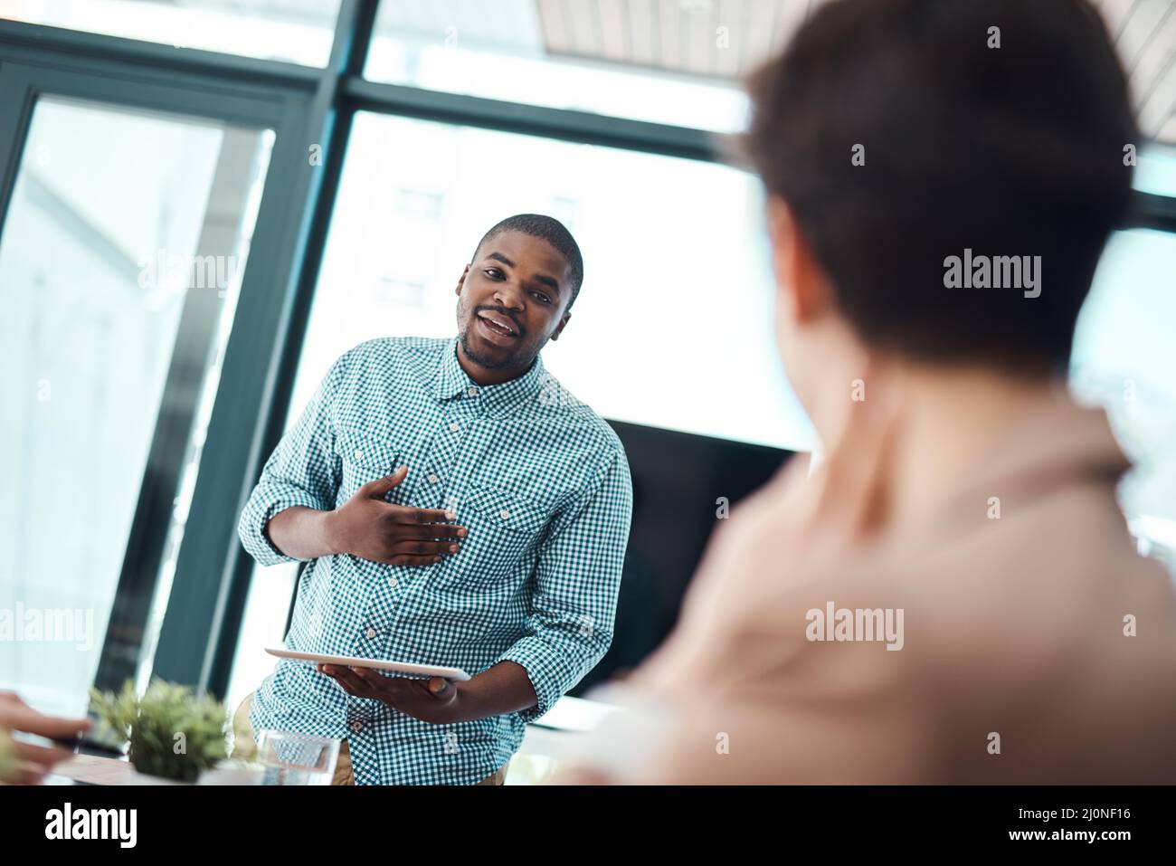 Aquí me he dado esta increíble idea Fotografía de un joven hombre de negocios que hace una presentación a sus colegas en una oficina. Foto de stock