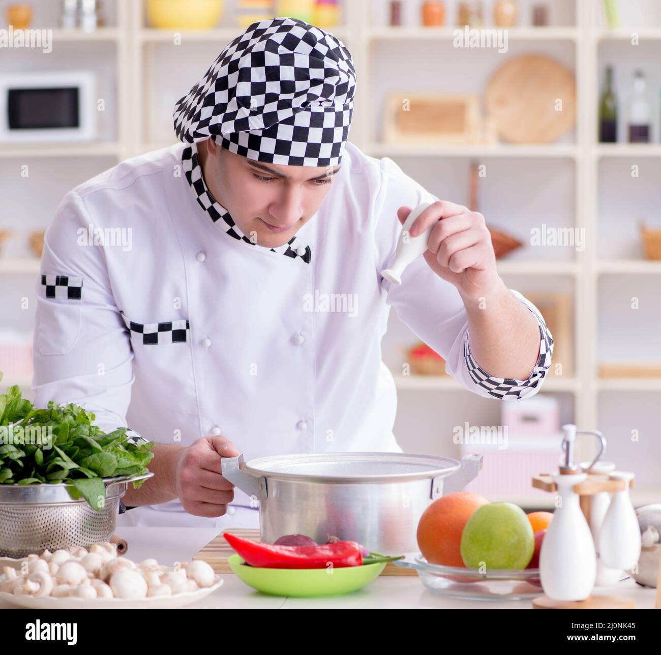 Macho joven cocinero trabajando en la cocina Foto de stock