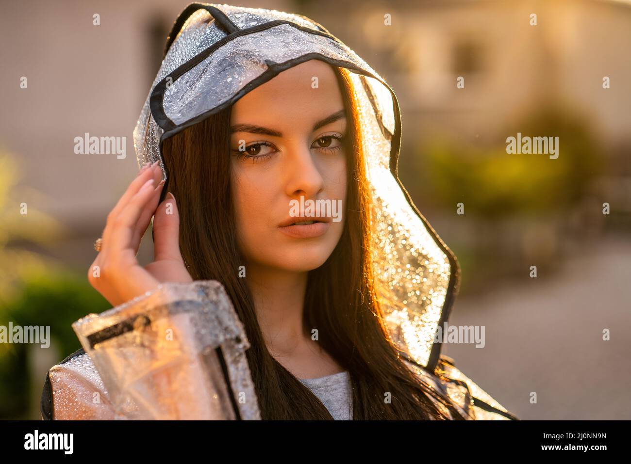 Joven hermosa mujer con capucha impermeable en el día de lluvia Foto de stock