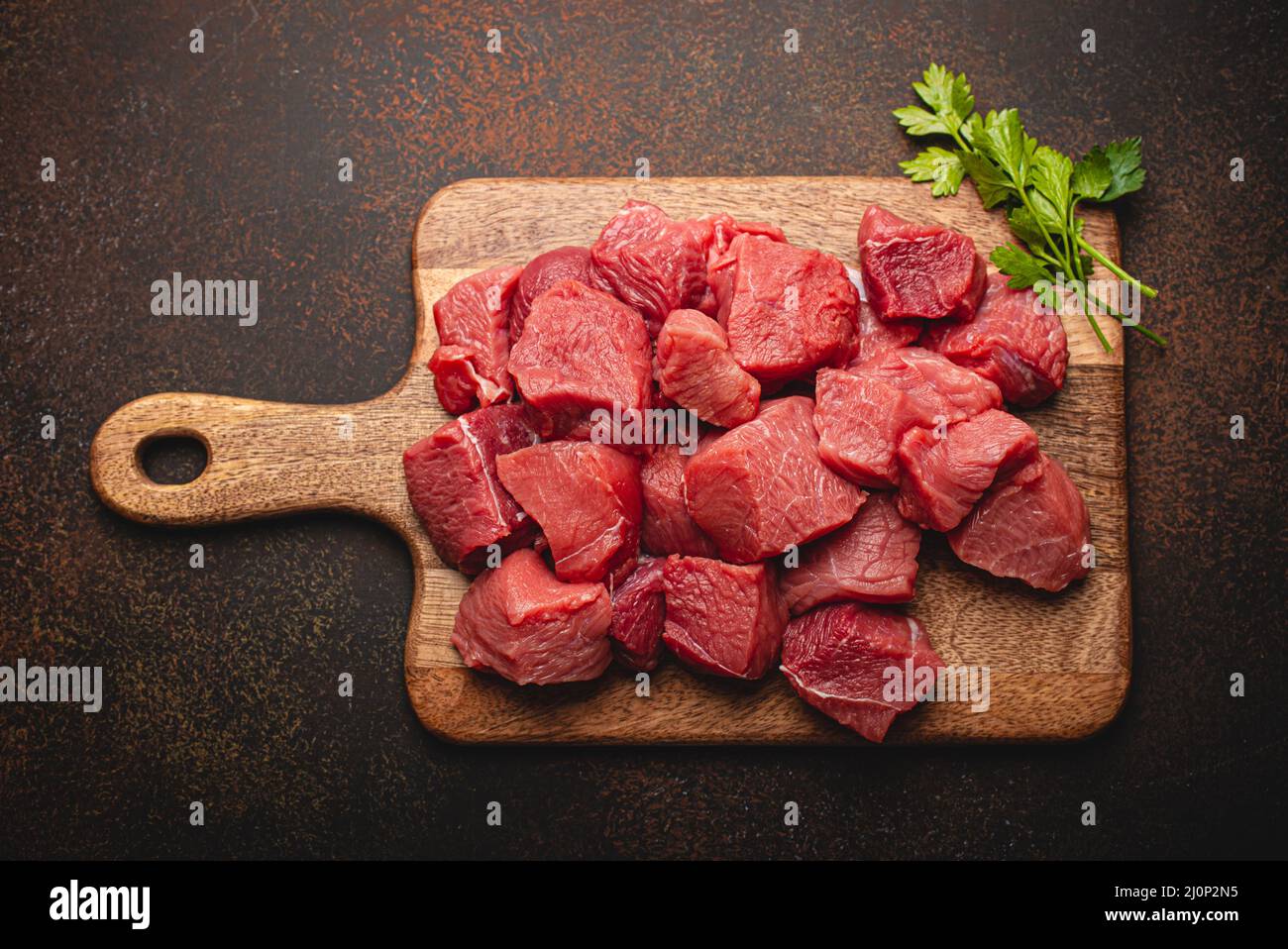 Dados de carne cruda de ternera para guisar sobre tabla de cortar de madera  Fotografía de stock - Alamy