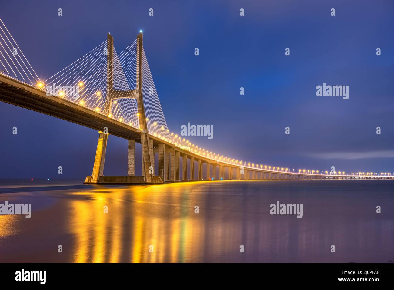El imponente puente de cable Vasco da Gama, cruzando el río Tajo en Lisboa, Portugal, por la noche Foto de stock