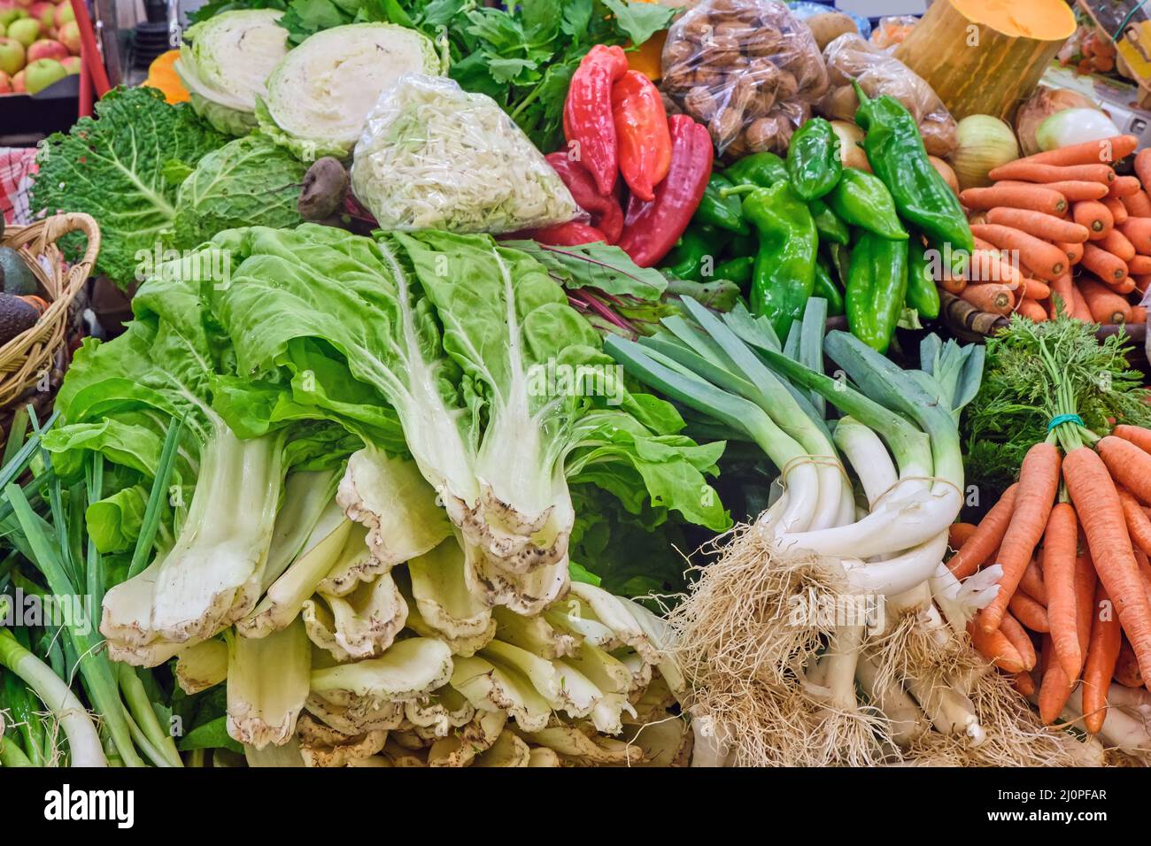 Gran variedad de verduras frescas y ensalada vista en un puesto de mercado Foto de stock