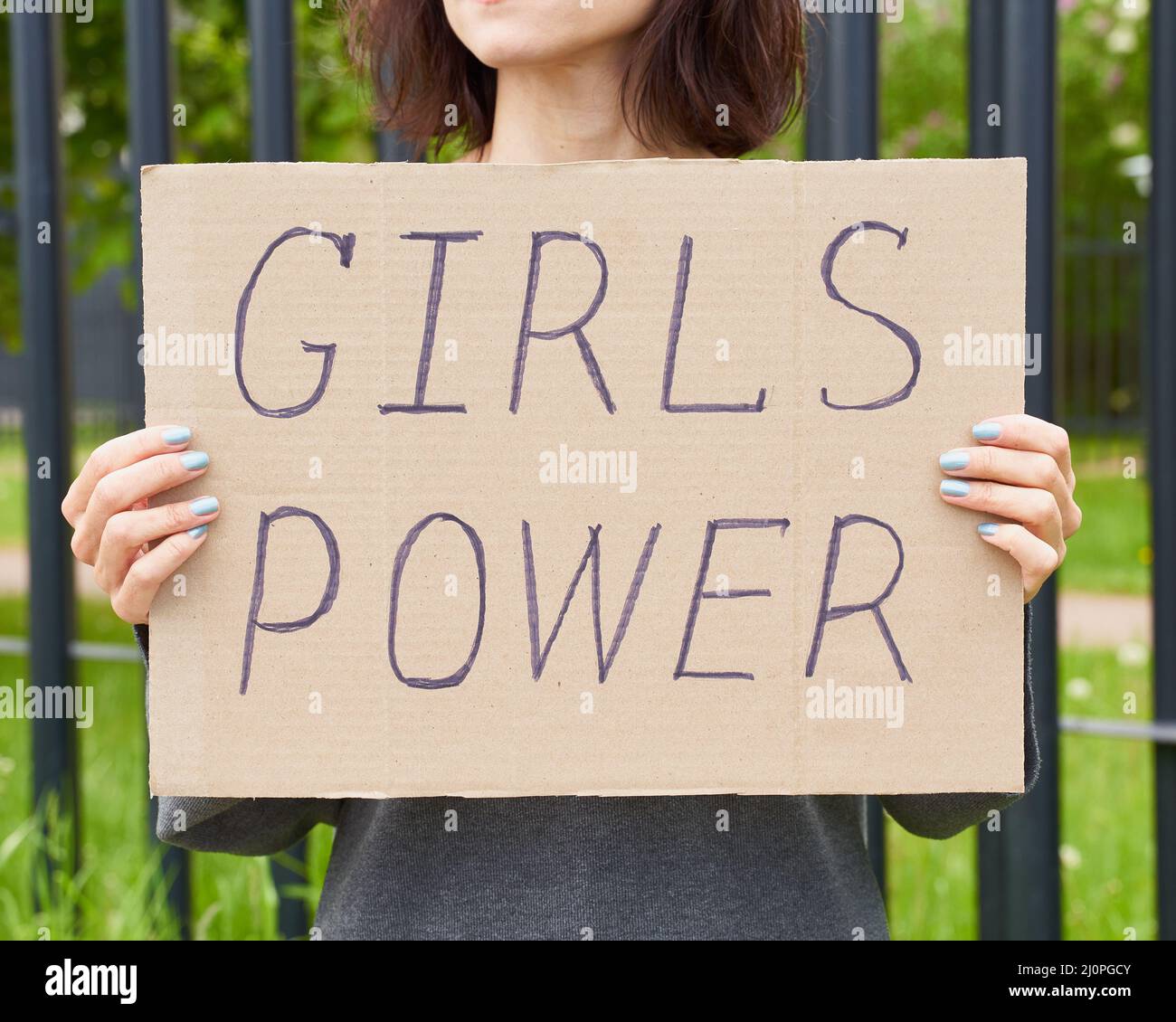 Concepto de energía de la muchacha. Una persona irreconocible tiene un signo con texto sobre el feminismo Foto de stock