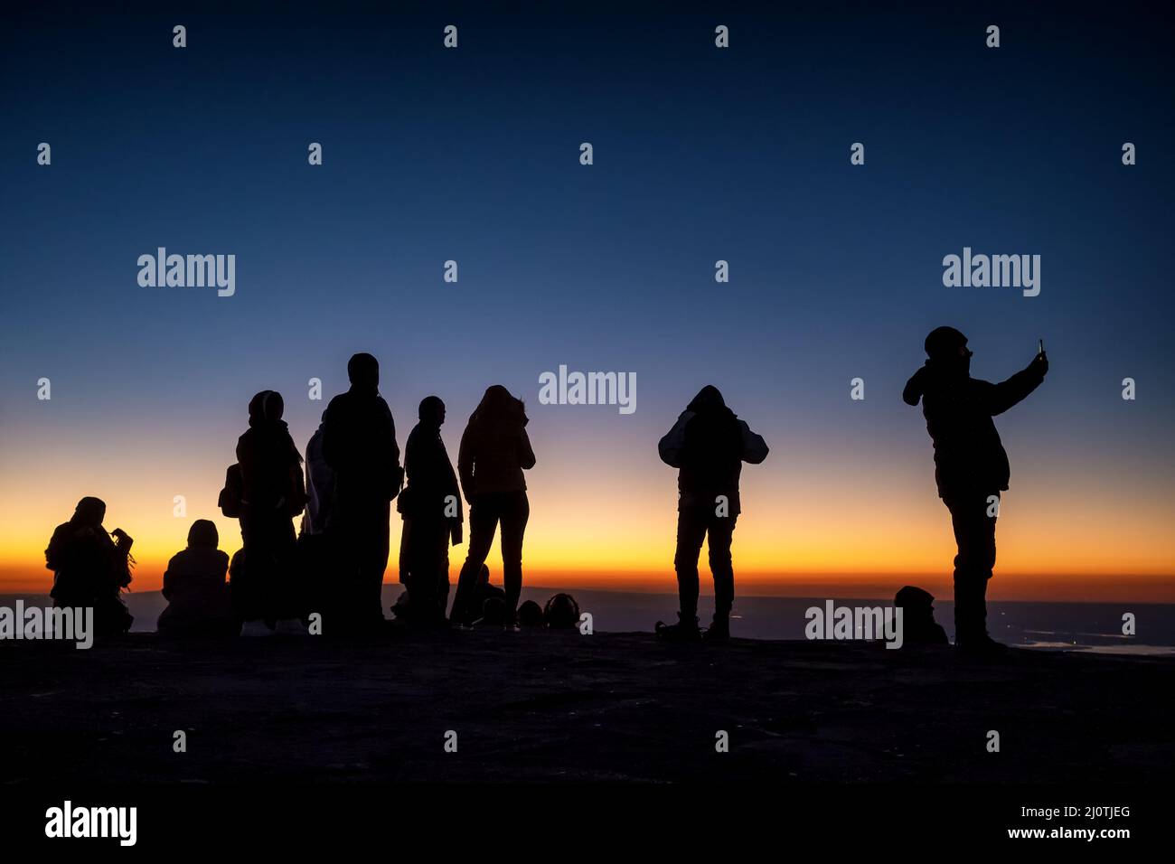 Silueta de personas no identificadas en la cima de la montaña esperando el amanecer Foto de stock