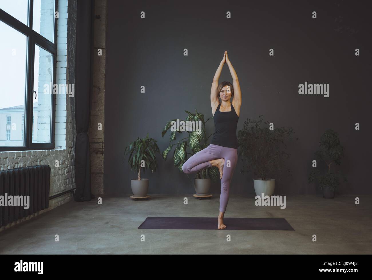 Consciente del cuerpo. Cuerpo humano, posición física, concepto de bienestar. Yoga, la mujer joven está parada en una asana. Foto de stock
