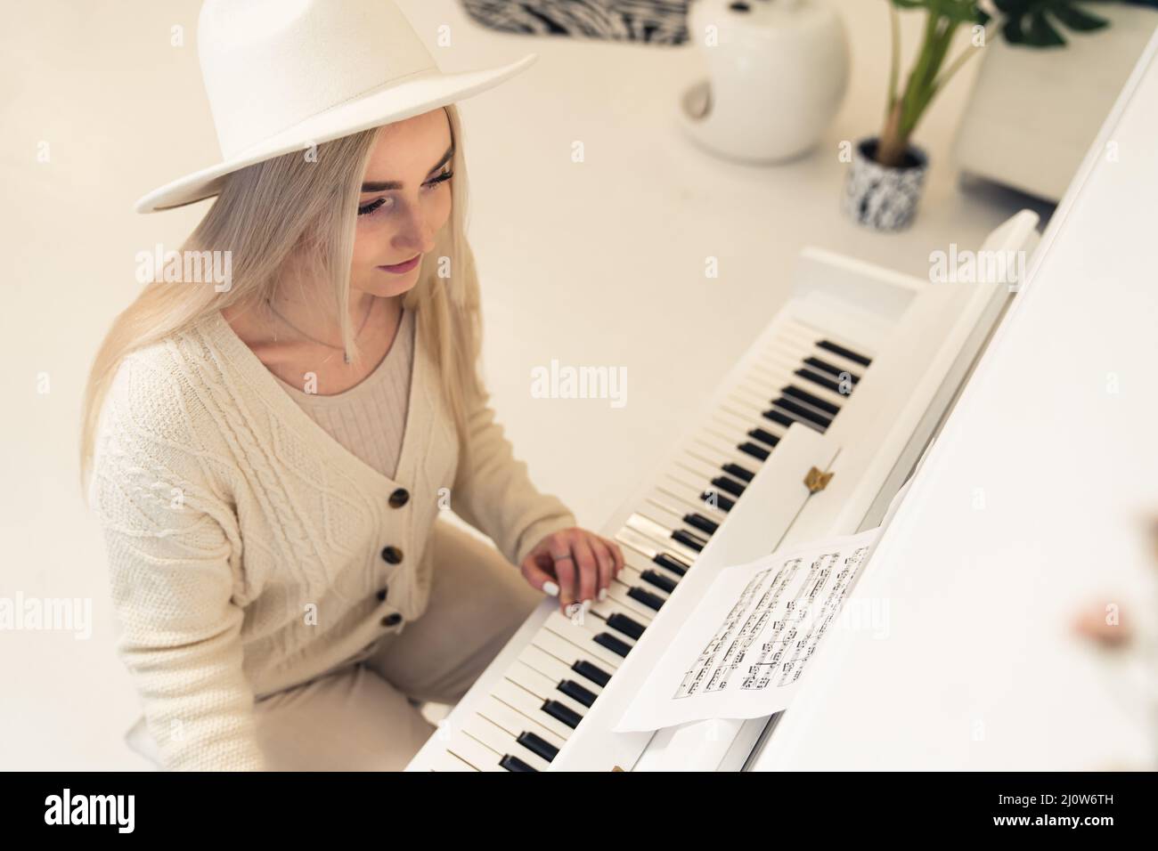 Mujer joven rubia caucásica con ropa ligera tocando el espacio de copia de piano . Fotografías de alta calidad Foto de stock