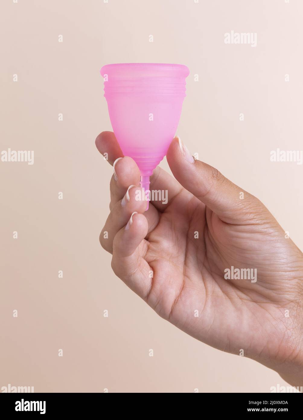 Mano de cerca sosteniendo la taza menstrual rosa. Fotografías de alta calidad Foto de stock