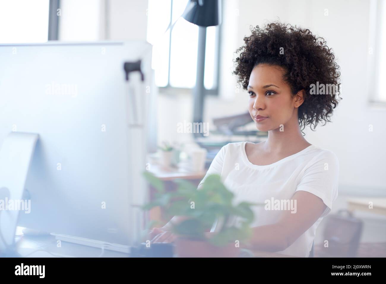 Mujer moderna para soluciones empresariales modernas. Mujer segura trabajando en su escritorio en un espacio de oficina abierto. Foto de stock