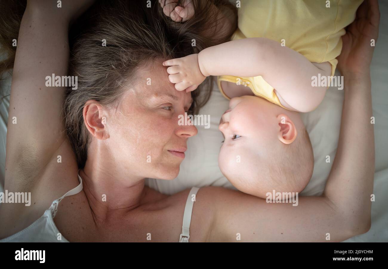 la madre y el bebé descansan sobre la cama, el concepto de maternidad, el día de la madre Foto de stock