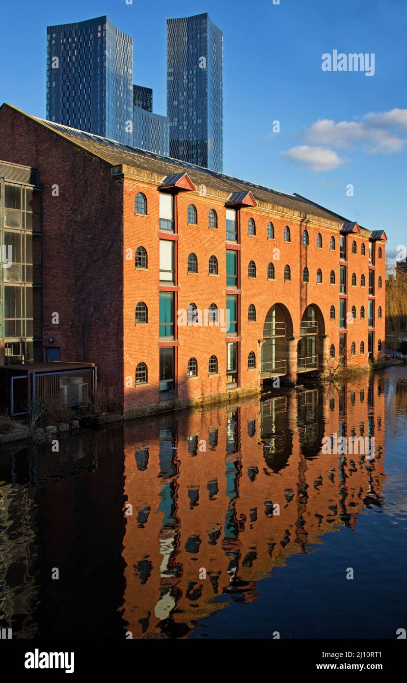 La yuxtaposición de la arquitectura vieja y nueva en Castlefield, Manchester, con el molino reformado reflejado en el agua del canal Foto de stock