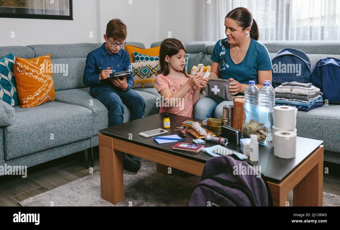 Madre preparando una mochila de emergencia con sus hijos Foto de stock