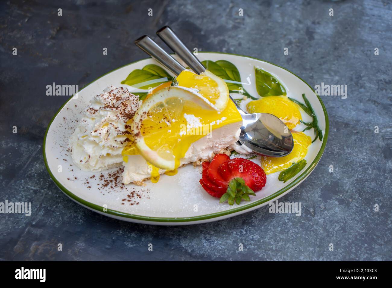 Rodaja de pastel de limón con fresa y crema batida Foto de stock