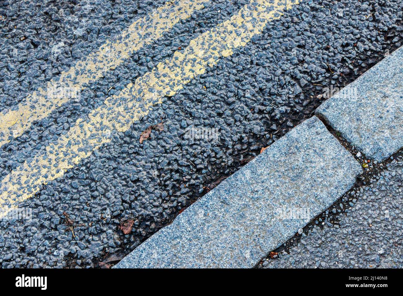 Primer plano de líneas amarillas dobles en una carretera de orugas y bordillas, diagonales Foto de stock